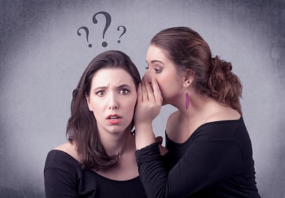 A teenager girl looking confused with drawn question marks above the head, while a girlfriend whispers something in her ear concept