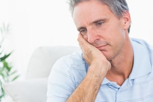 Depressed man thinking at home on couch