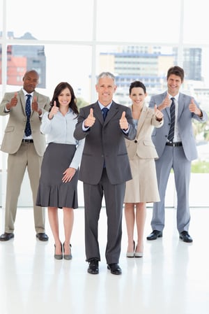 Smiling business team standing together with their thumbs up in success