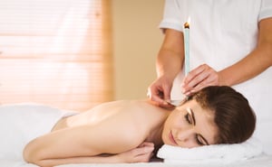 Young woman getting ear candling treatment in therapy room