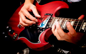 electric guitar close up with fingers playing it