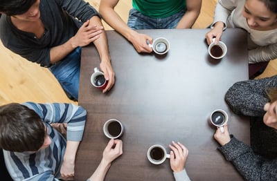 Students sitting around table drinking coffee in college cafe